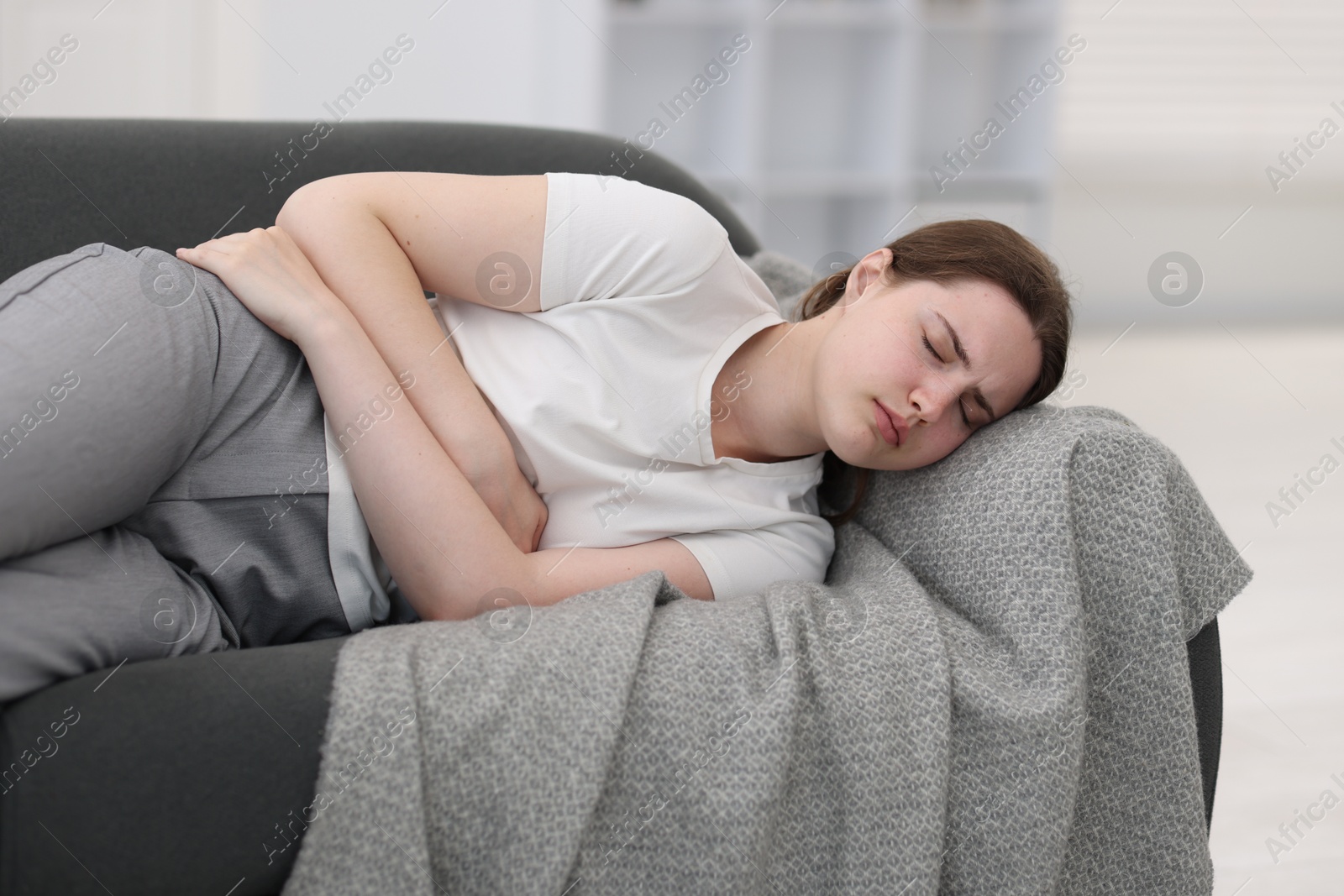Photo of Young woman suffering from stomachache at home