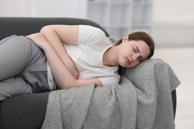 Photo of Young woman suffering from stomachache at home