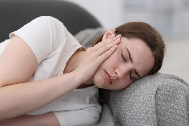 Photo of Young woman suffering from headache at home