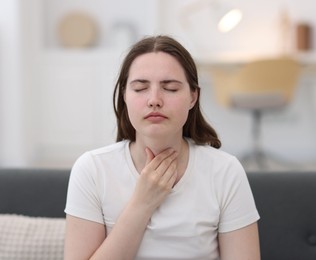 Photo of Young woman suffering from sore throat at home