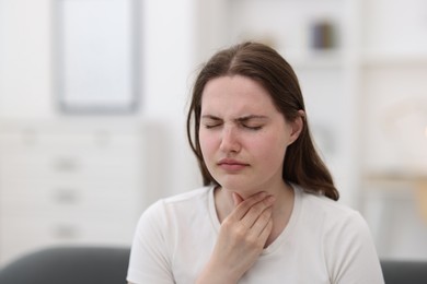 Photo of Young woman suffering from sore throat at home