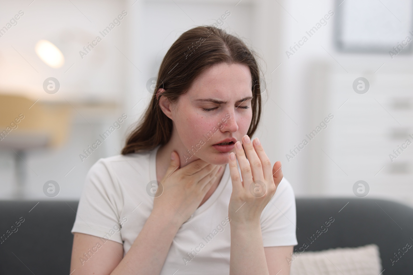 Photo of Young woman suffering from sore throat at home