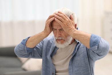 Photo of Senior man suffering from headache at home