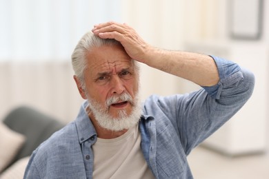 Photo of Senior man suffering from headache at home