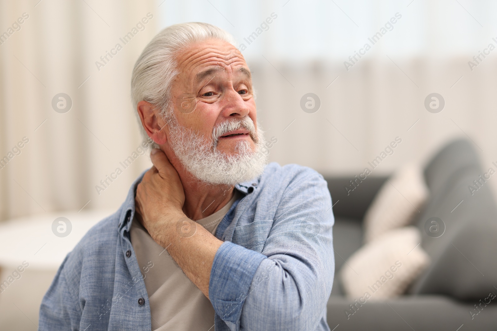 Photo of Senior man suffering from neck pain at home