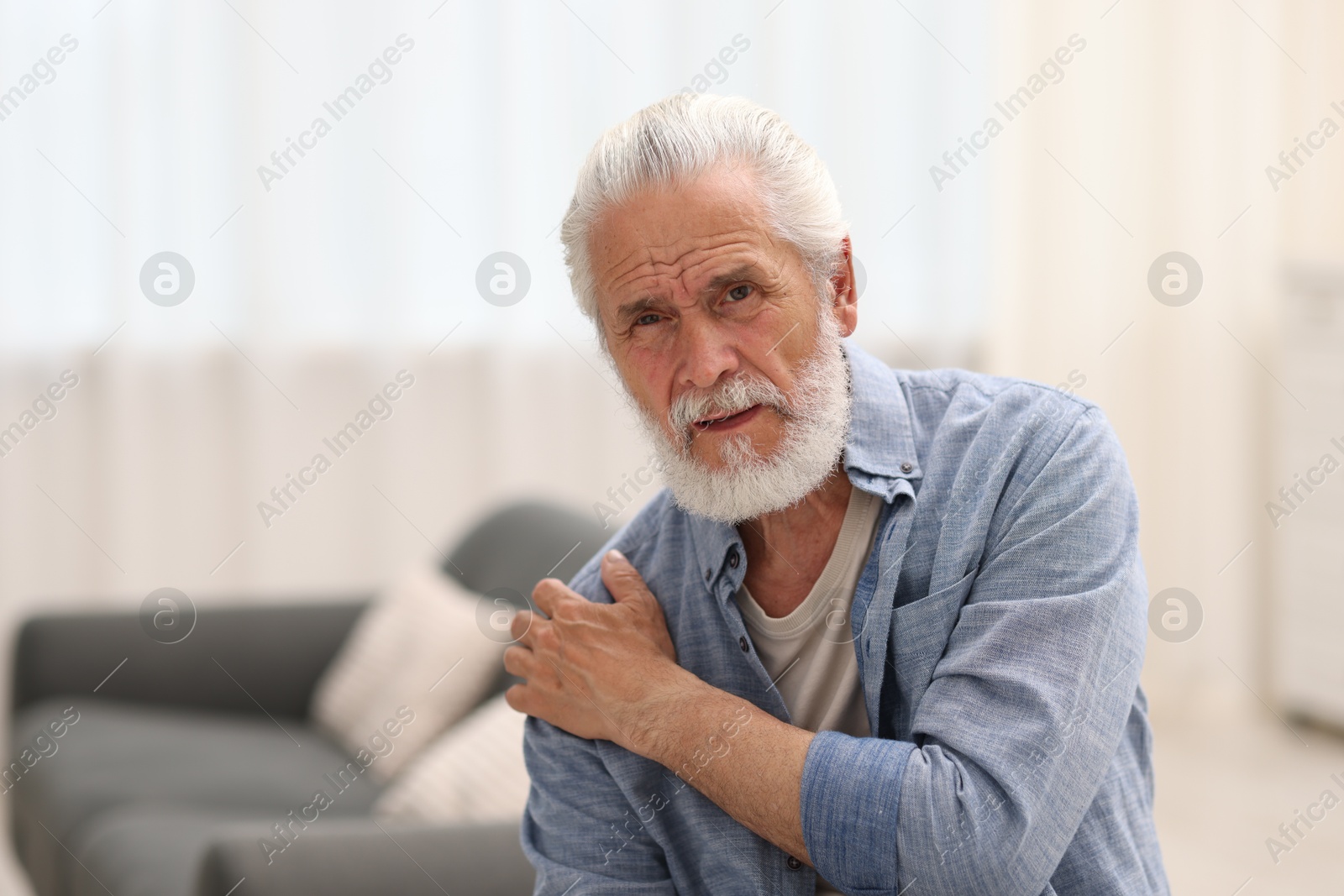 Photo of Senior man suffering from shoulder pain at home