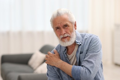 Photo of Senior man suffering from shoulder pain at home