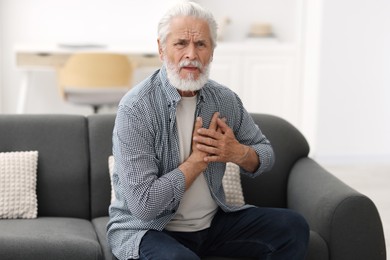 Photo of Senior man suffering from chest pain at home