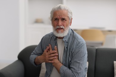 Photo of Senior man suffering from chest pain at home