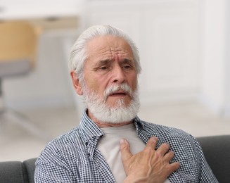 Photo of Senior man suffering from chest pain at home