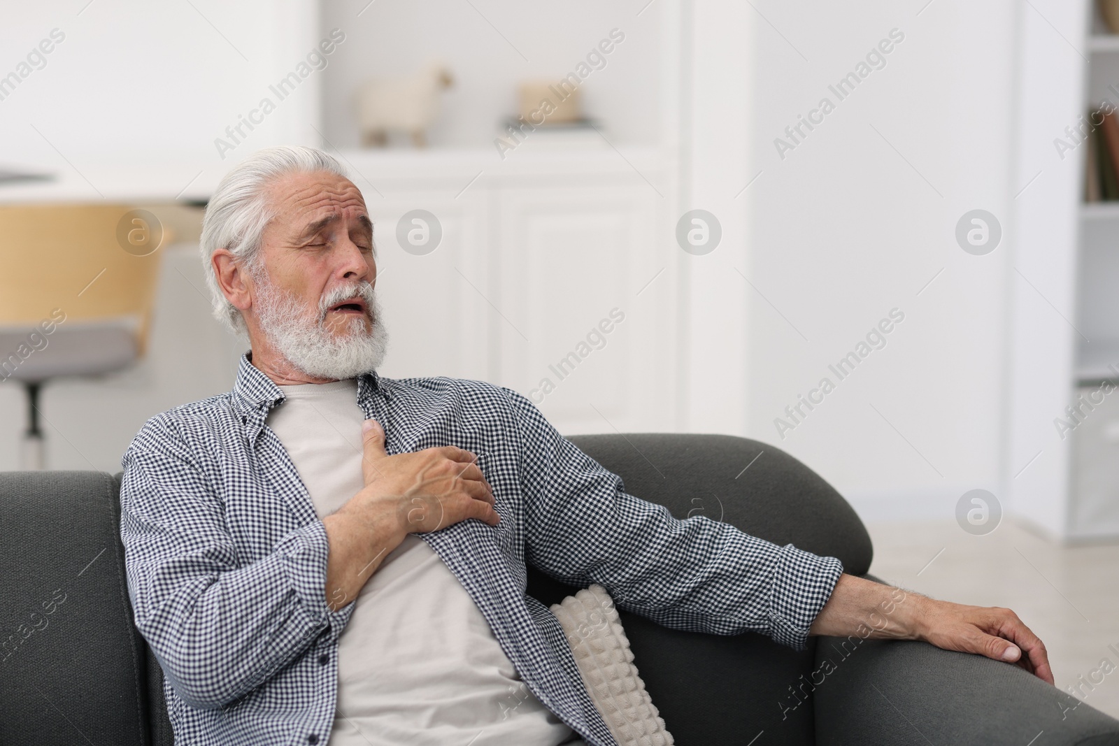 Photo of Senior man suffering from chest pain at home