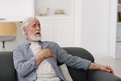 Photo of Senior man suffering from chest pain at home
