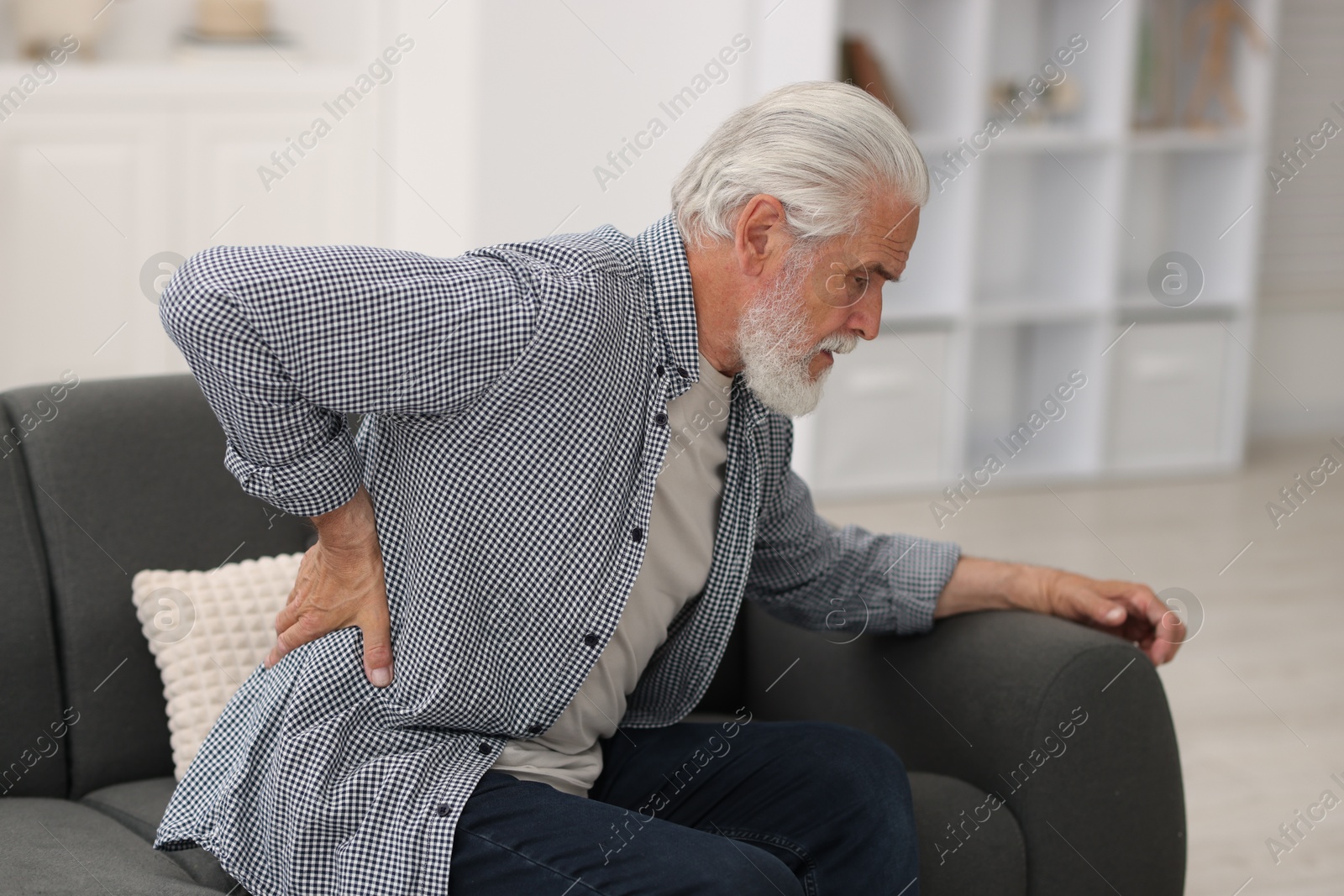 Senior man suffering from back pain at home Photo of Senior man suffering from back pain at home