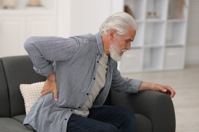 Photo of Senior man suffering from back pain at home