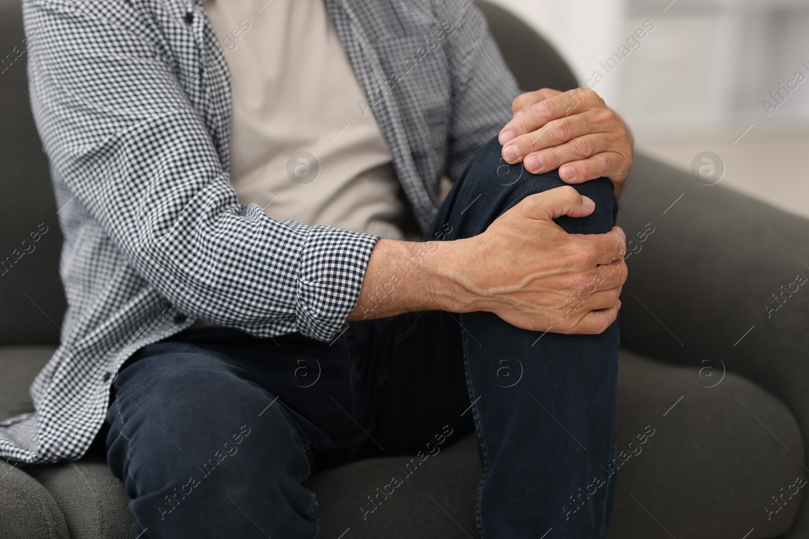 Senior man suffering from knee pain at home, closeup Photo of Senior man suffering from knee pain at home, closeup