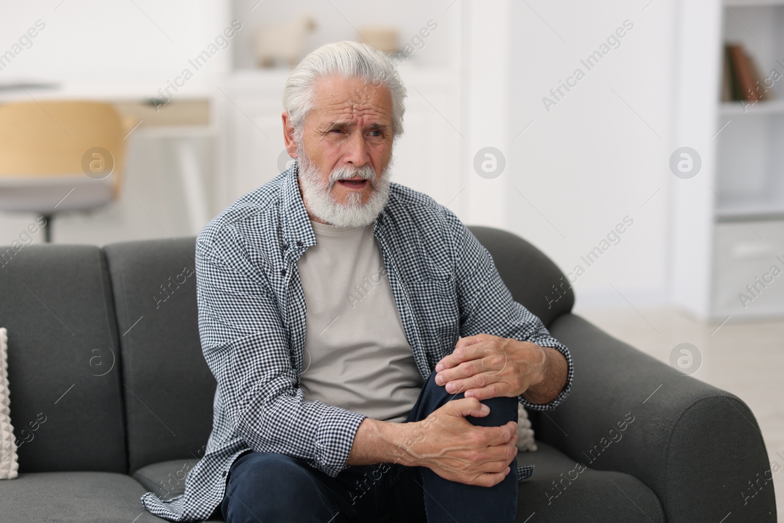 Senior man suffering from knee pain at home Photo of Senior man suffering from knee pain at home