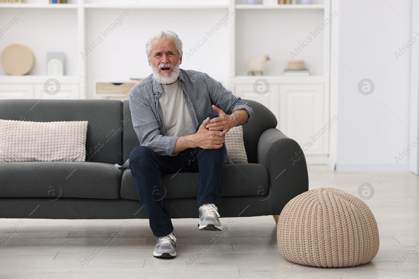 Photo of Senior man suffering from knee pain at home