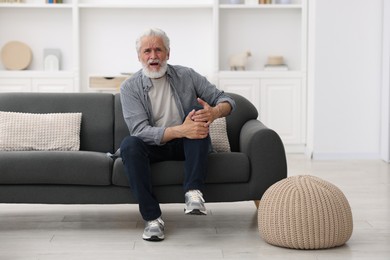 Photo of Senior man suffering from knee pain at home