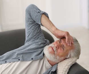 Photo of Senior man suffering from headache at home