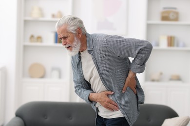 Photo of Senior man suffering from back pain at home