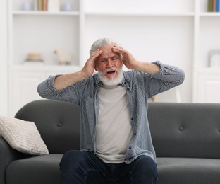 Photo of Senior man suffering from headache at home