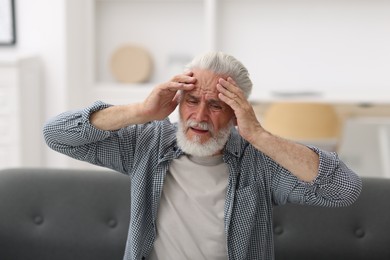 Photo of Senior man suffering from headache at home