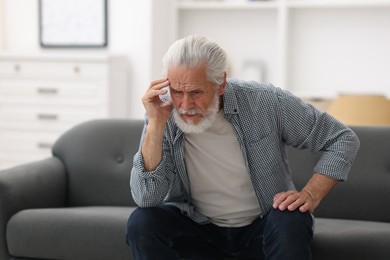 Photo of Senior man suffering from headache at home