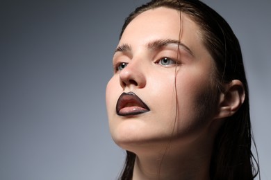 Photo of Beautiful young woman with black lip liner on light grey background, closeup. Space for text