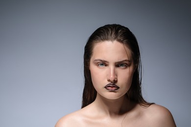 Photo of Beautiful young woman with black lip liner on light grey background, space for text