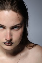 Photo of Beautiful young woman with black lip liner on light grey background, closeup
