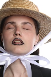 Photo of Beautiful young woman with black lip liner wearing straw hat on white background, closeup