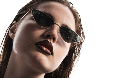 Photo of Beautiful young woman with black lip liner wearing wet sunglasses on white background, closeup