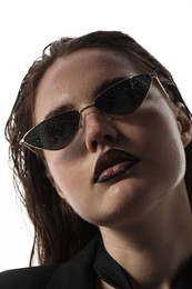 Photo of Beautiful young woman with black lip liner wearing wet sunglasses on white background, closeup