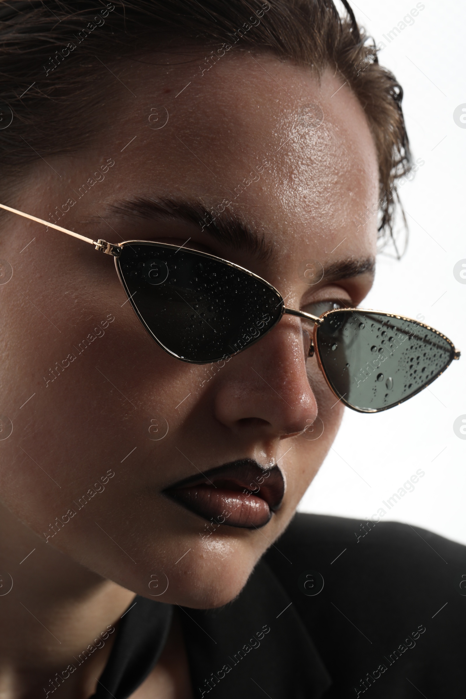 Beautiful young woman with black lip liner wearing wet sunglasses on white background, closeup Photo of Beautiful young woman with black lip liner wearing wet sunglasses on white background, closeup
