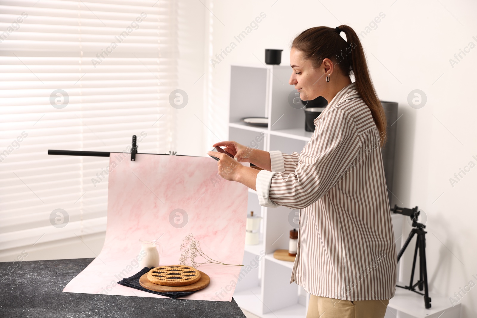 Photo of Woman taking picture of tasty pie and milk in studio. Professional food photography