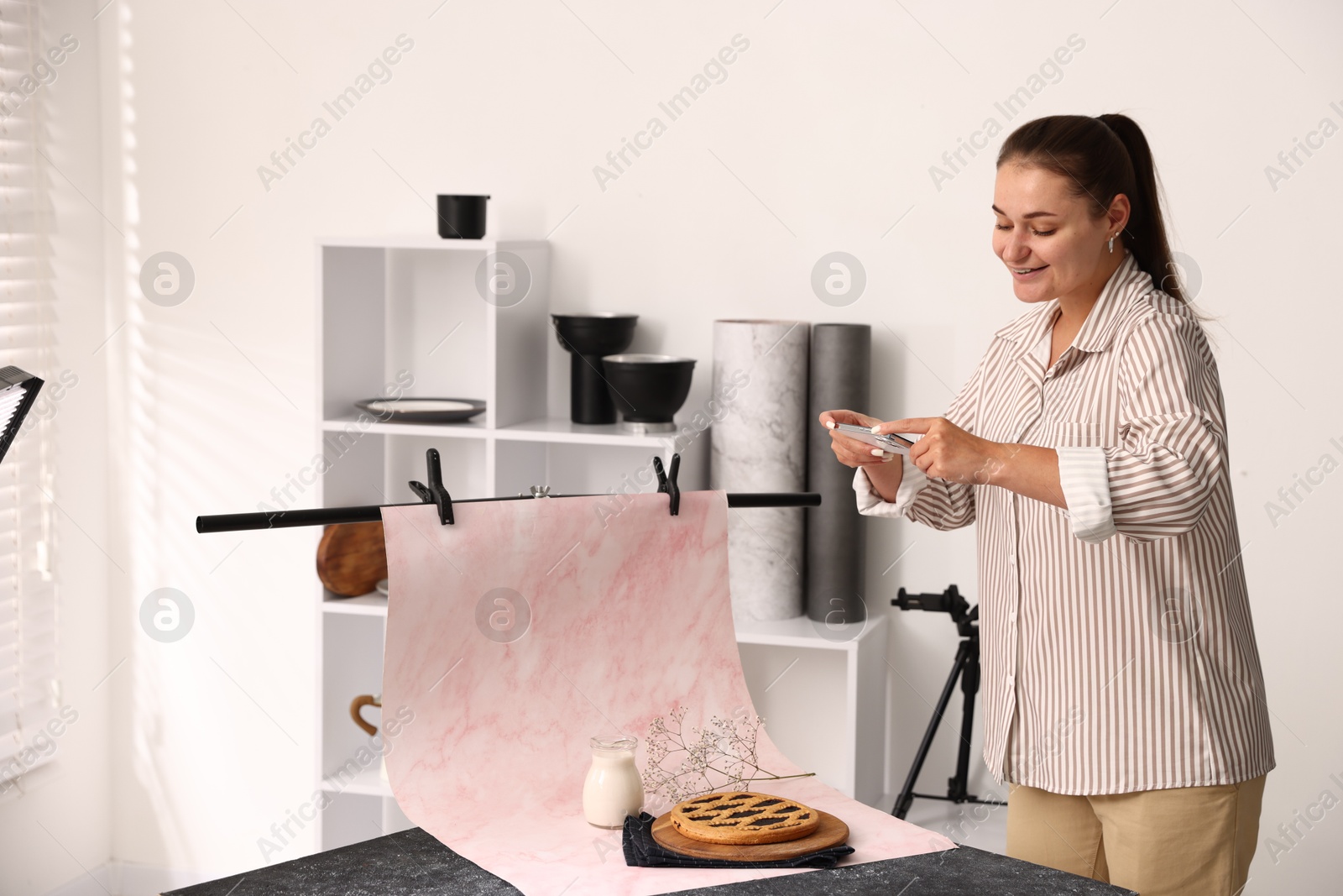 Photo of Woman taking picture of tasty pie and milk in studio. Professional food photography