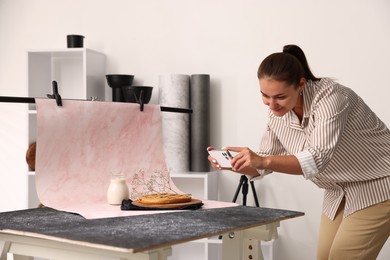 Photo of Woman taking picture of tasty pie and milk in studio. Professional food photography