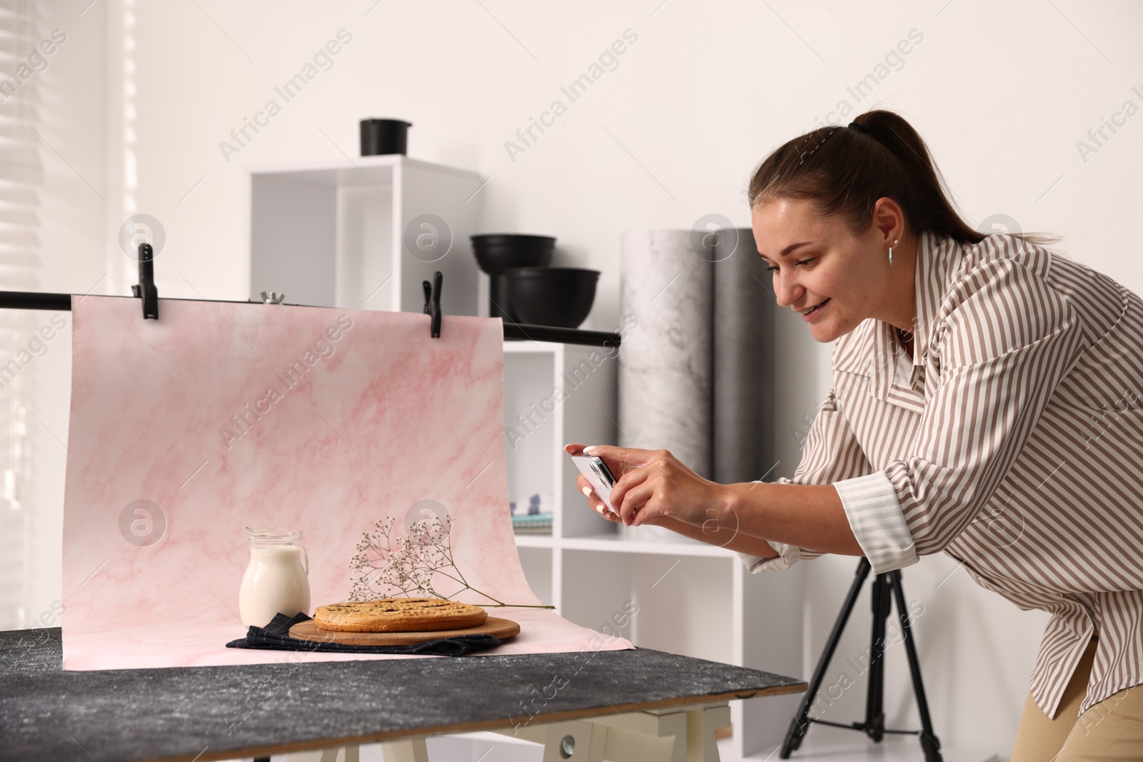 Photo of Woman taking picture of tasty pie and milk in studio. Professional food photography
