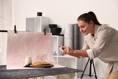 Photo of Woman taking picture of tasty pie and milk in studio. Professional food photography