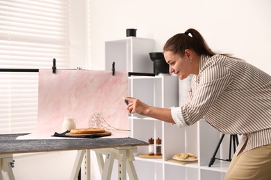 Photo of Woman taking picture of tasty pie and milk in studio. Professional food photography