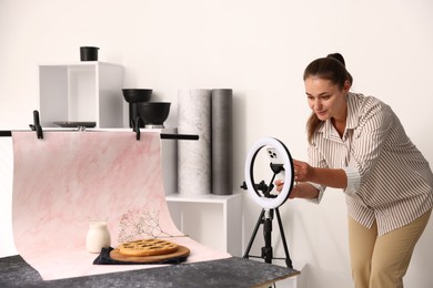 Photo of Woman taking picture of tasty pie and milk in studio. Professional food photography