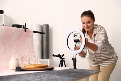 Photo of Woman taking picture of tasty pie and milk in studio, selective focus. Professional food photography