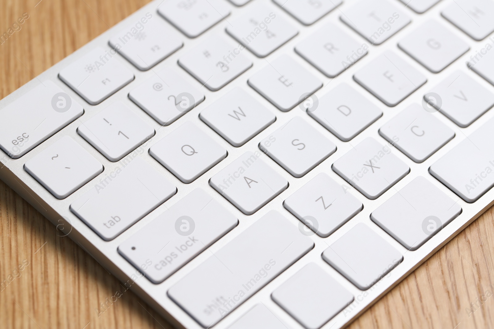 Modern white wireless keyboard on wooden table, closeup Photo of Modern white wireless keyboard on wooden table, closeup