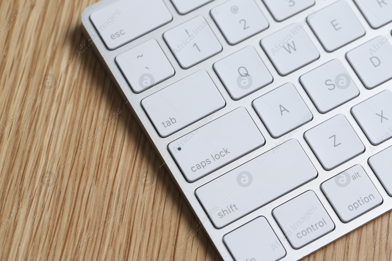 Modern white wireless keyboard on wooden table, closeup. Space for text Photo of Modern white wireless keyboard on wooden table, closeup. Space for text