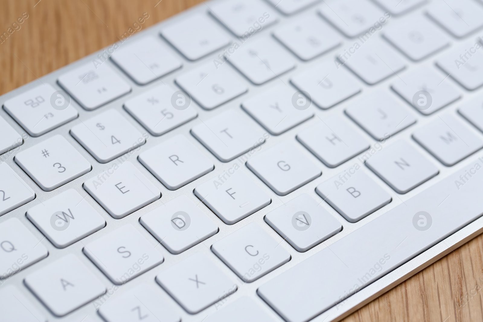 Modern white wireless keyboard on wooden table, closeup Photo of Modern white wireless keyboard on wooden table, closeup