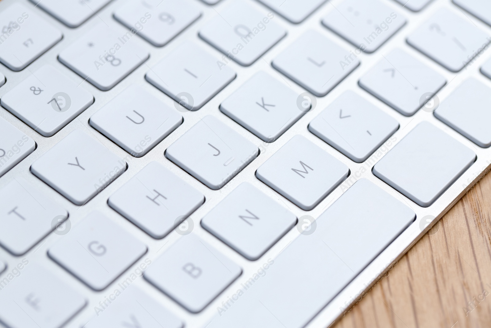 Modern white wireless keyboard on wooden table, closeup Photo of Modern white wireless keyboard on wooden table, closeup
