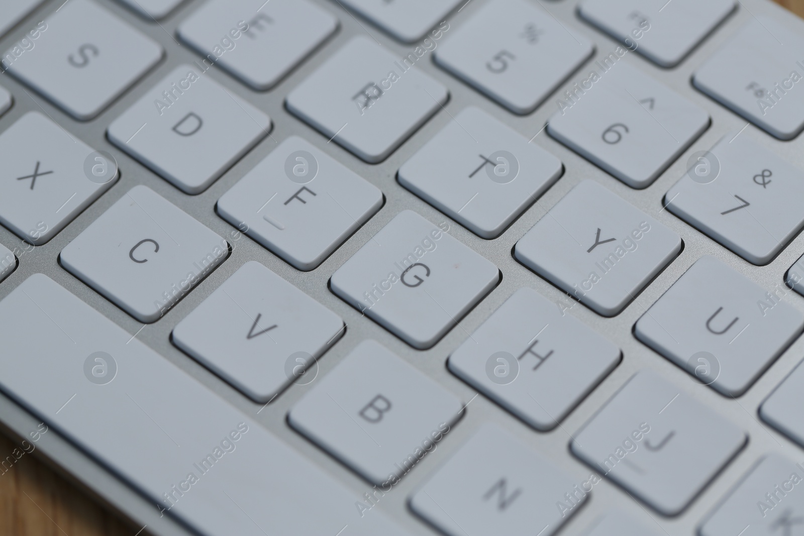 Modern white wireless keyboard on wooden table, closeup Photo of Modern white wireless keyboard on wooden table, closeup