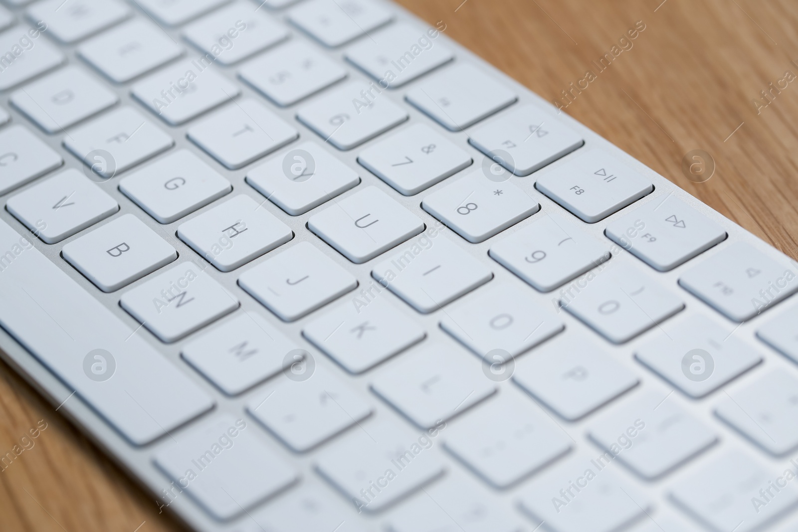 Modern white wireless keyboard on wooden table, closeup Photo of Modern white wireless keyboard on wooden table, closeup