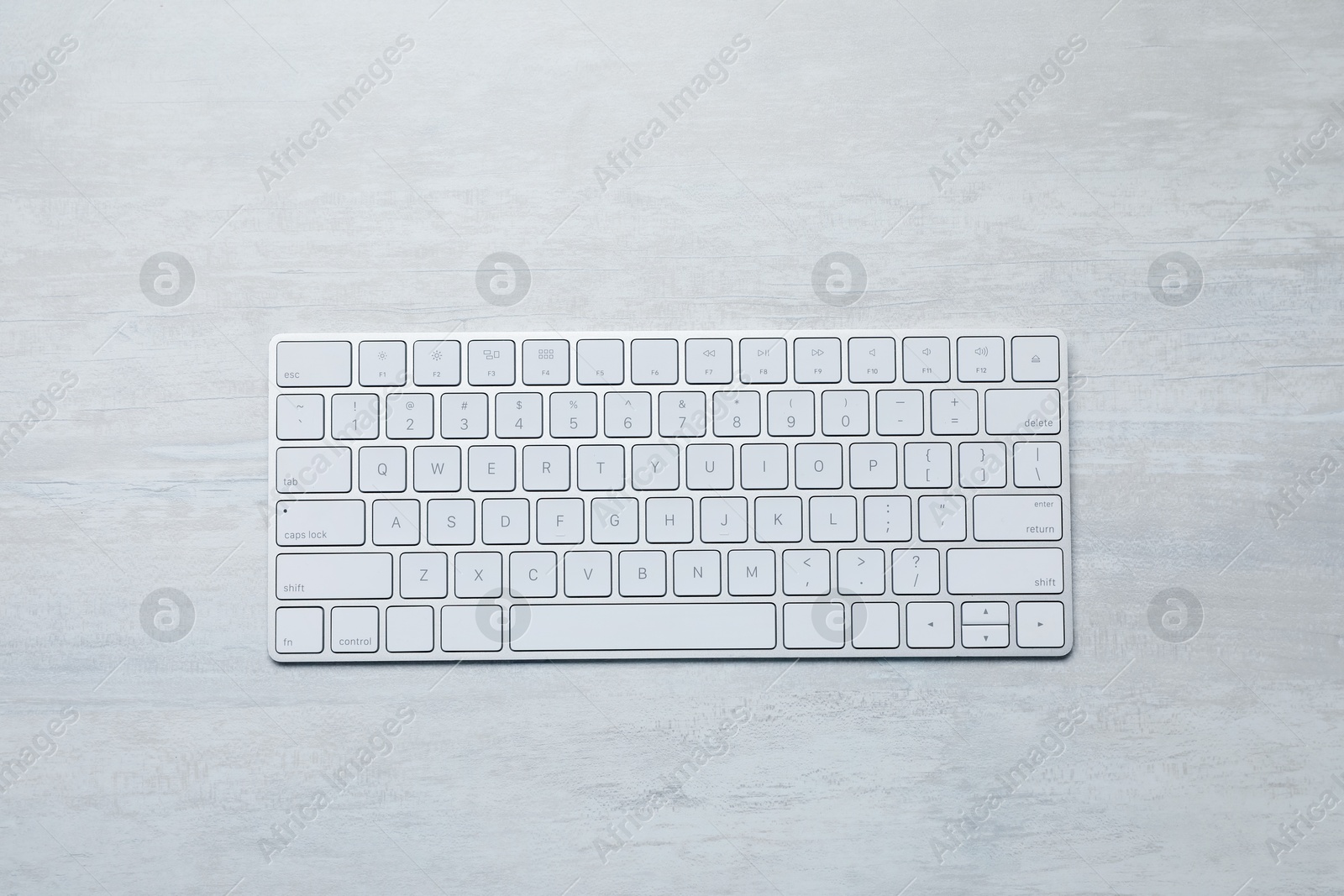 Photo of Modern wireless keyboard on white wooden table, top view