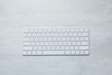 Photo of Modern wireless keyboard on white wooden table, top view